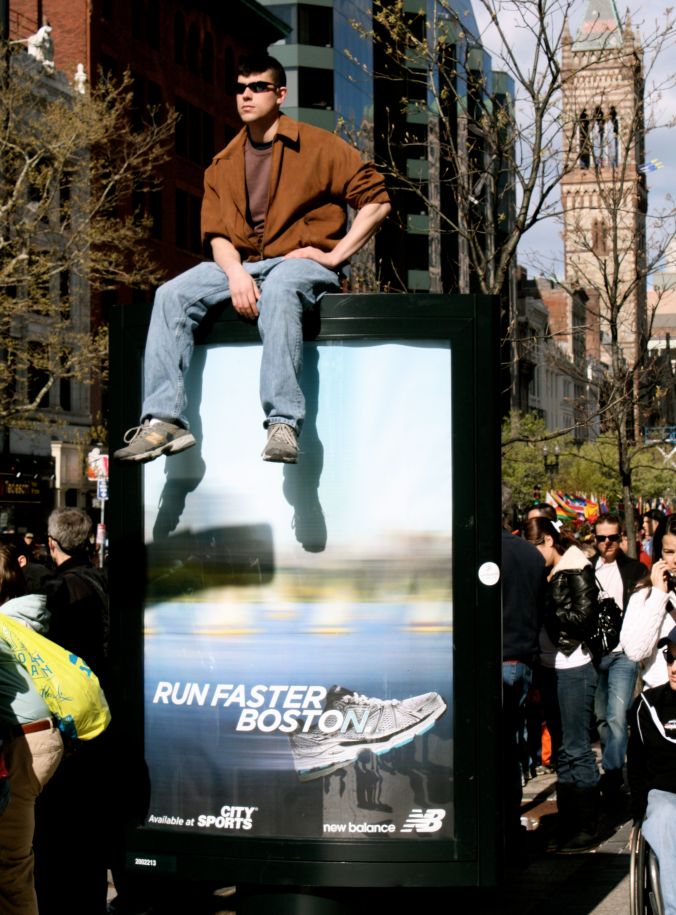boston marathon man sitting on sign