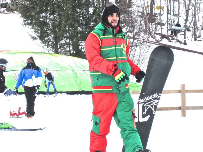 wachusett mountain ski slope man in green and red snow boarding jump suit